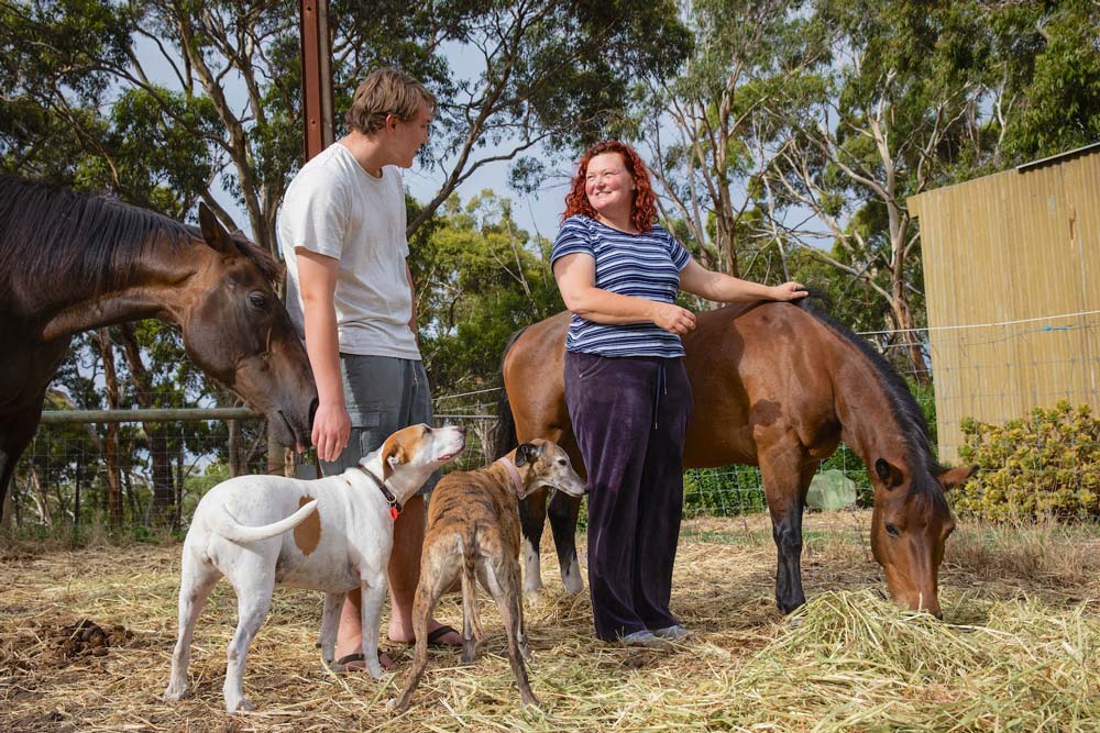 Two people looking after a horse and dogs