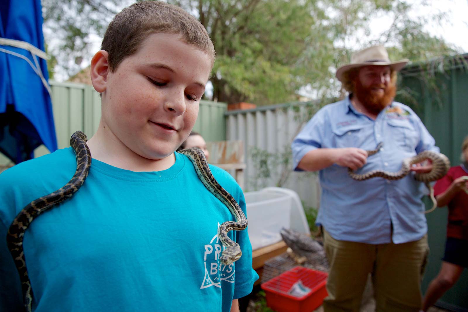 A young boy with a snake around his neck